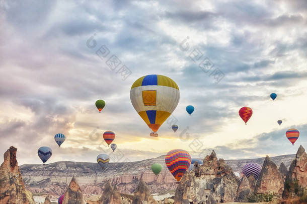 大量的气球在清晨的天空中飞在黎明的阳光下。天空中的气球气球在山上的云层中。土耳其的主要吸引力。美丽的景色