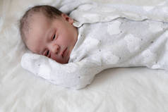 刚出生的婴儿在出生的头几分钟睁大眼睛躺在背上。一个新生的、带有原始油脂痕迹的婴儿斜视着他的眼睛。宝宝看起来像在眯着眼.