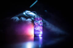 鸡尾酒杯溅在黑暗的色调烟雾背景或五颜六色的鸡尾酒在玻璃。派对俱乐部娱乐。混合光.
