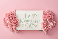 贺卡的顶部视图与快乐的妇女天字母和粉红色的康乃馨在粉红色的背景