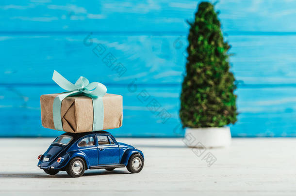 特写镜头玩具车与礼品盒和微型圣诞树在蓝色木背景