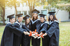 大学校园里穿着毕业礼服拿着毕业证书的快乐学生