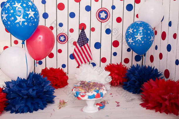 带着纸制花环、气球、纸球、汤匙、意大利面和<strong>奶油蛋糕</strong>的照片区。生日<strong>蛋糕</strong>。把<strong>蛋糕</strong>砸了一年。红色、蓝色、白色. 