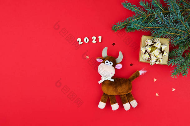 公牛是<strong>2021</strong>年新年的象征。红色节日背景上的毛绒玩具，有冷杉枝条和礼物。中国农历<strong>2021</strong>年牛年.