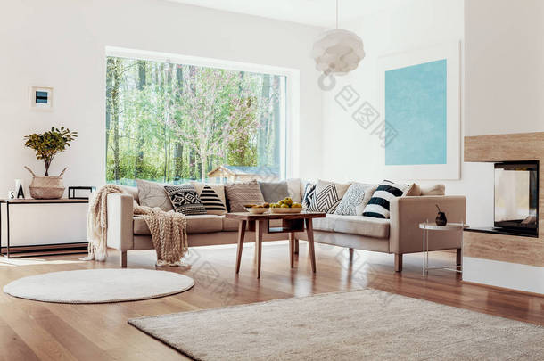 在一个宽敞的, 白色起居室的地板上的米色地毯内饰与现代壁炉在一个舒适的<strong>沙发</strong>与图案枕头前.