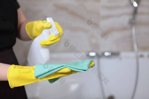 在昂贵的旅馆或家里提供清洁服务。穿着制服和橡胶手套的女人。浴室里的清洁和卫生。无法辨认的照片。只有一只手复制空间.
