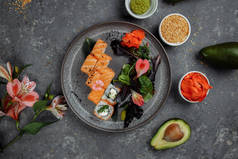 美味的新鲜寿司卷与鲑鱼和费城奶酪灰色盘在黑暗的石头背景。日本传统海鲜，健康食品概念.