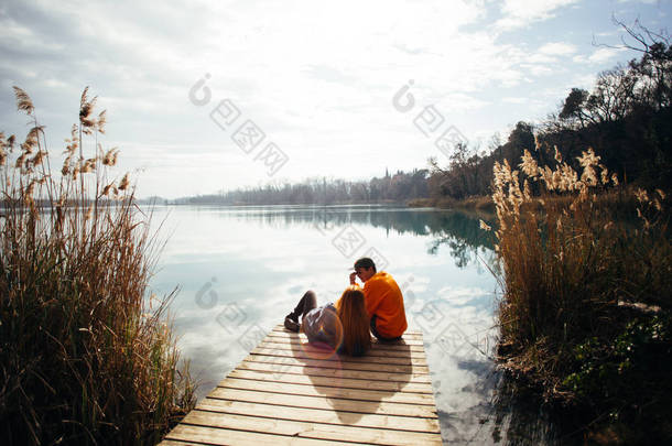 年轻的时髦情侣禧, 爱鸟<strong>坐</strong>在码头上的公园俯瞰大湖或河在秋季季节。<strong>拥</strong>抱和<strong>拥</strong>抱舒适和浪漫, 谈论未来计划和旅行目的地