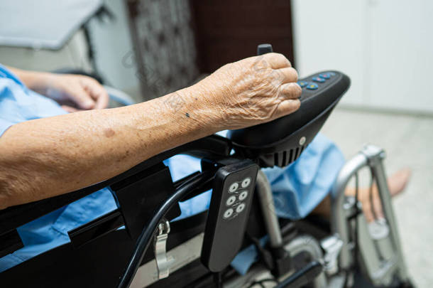 亚洲老年妇女病人或老年妇女坐在电动轮椅上，远程控制在护理病房，健康有力的医疗理念 
