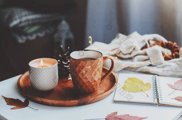 <strong>舒适</strong>的秋天或冬天的早晨在家。静止不动的生活细节与一杯茶，蜡烛，素描书与水族馆和<strong>温暖</strong>的毛衣。斯堪的纳维亚海格概念