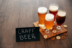 不同种类的工艺啤酒和小吃木托盘上的眼镜