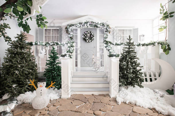 房子入口装饰为假日。圣诞节装饰。在栏杆上的冷杉树枝和灯的花环