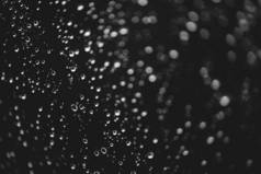 脏窗户玻璃与雨滴。大气单色深色背景，散景带雨滴。水滴和污渍特写。宏中的详细透明纹理。复制空间。雨天.