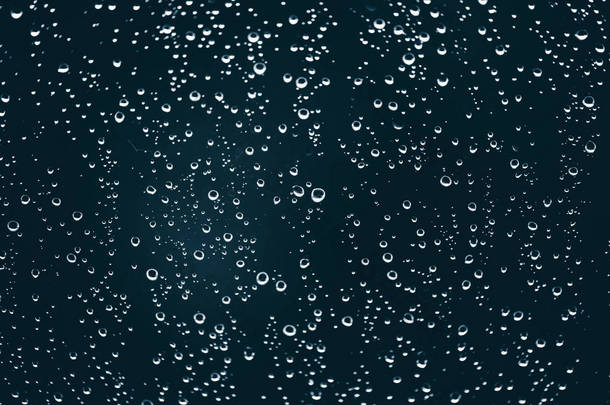 脏窗户<strong>玻璃</strong>与雨滴。大气蓝色背景与雨滴。水滴和污渍特写。宏中具有复制空间的详细透明纹理。雨天.