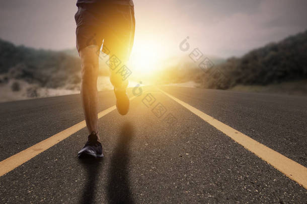 目标与奋斗理念，跑步者在阳光升起的道路上奔跑. 