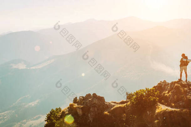背包小人影的登山健行者，带着美丽的全景呆在山顶上