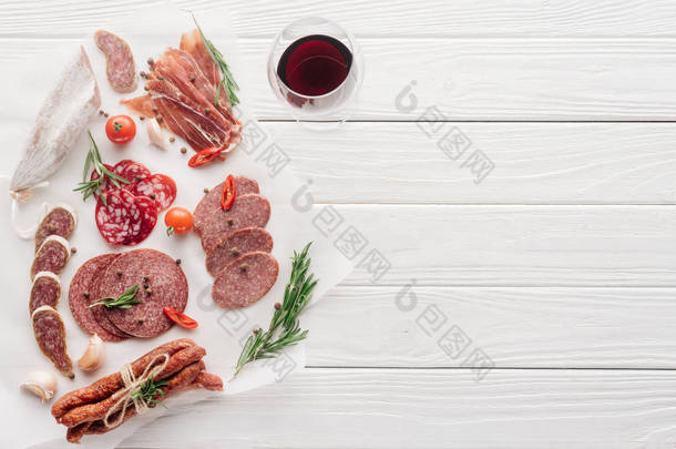 在白色木制桌面上加一杯<strong>红酒</strong>和各种肉类小吃的食物组合