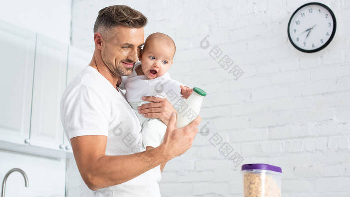 父亲抱着小女儿并显示奶瓶与牛奶