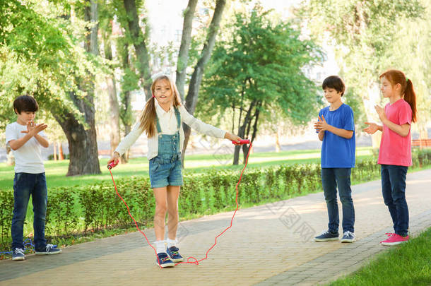 逗人喜爱的小孩子跳绳在公园
