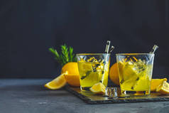柠檬酒精饮料鸡尾酒与冰, 柠檬和迷迭香草本植物在黑色的石头混凝土表面。传统的意大利自制柠檬酒精饮料利口酒利蒙切洛.