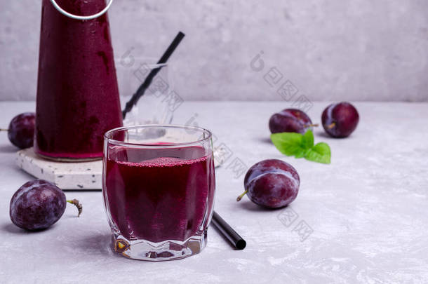 红色李子汁在玻璃杯的灰色石头<strong>背景</strong>与新鲜的水果。有选择的重点.