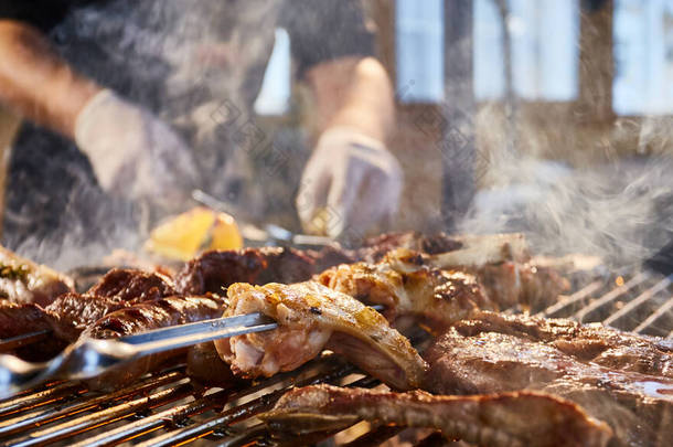 肉用格子烤架、排骨、木桩、香肠、边、鸡、明火、黑胡椒、烟、柴火、厨师<strong>手</strong>拿肉、<strong>手</strong>拿着<strong>手</strong>套、关门