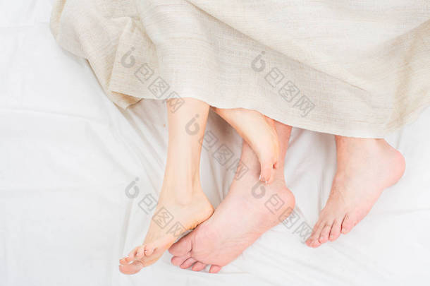 闭上赤脚的情侣双腿睡在卧室的白色床上的<strong>早晨</strong>