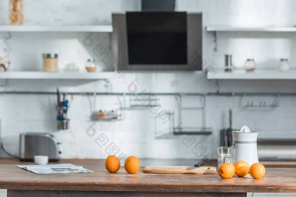 带榨汁机、玻璃和木桌上美味有机橙子的现代厨房 