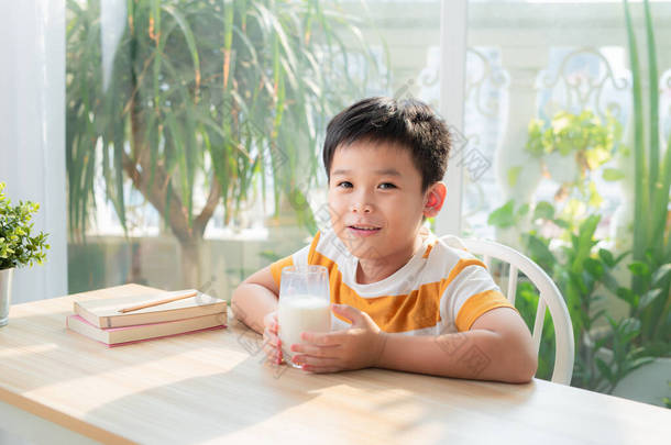 可爱的年轻的亚洲男孩，<strong>早上</strong>在家里吃早餐和喝牛奶；看着相机