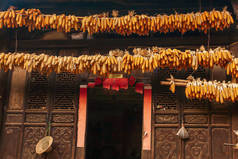 云南农村地区，中国古屋屋檐下挂着黄色的玉米芯，用于自然干燥.