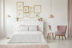 桌上的粉彩灯与花和粉红色扶手椅在妇女的卧室内部与床