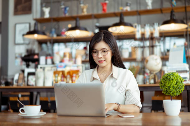 快乐<strong>自由</strong>职业者亚洲妇女工作使用数字笔记本电脑打字键盘在共同工作<strong>空间</strong>或咖啡馆.
