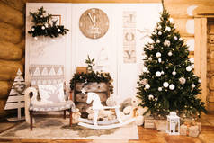 圣诞装饰：椅子，圣诞树，抽屉，钟，木制墙壁背景上的礼物。 圣诞摄影区。 有圣诞树的圣诞照片区.