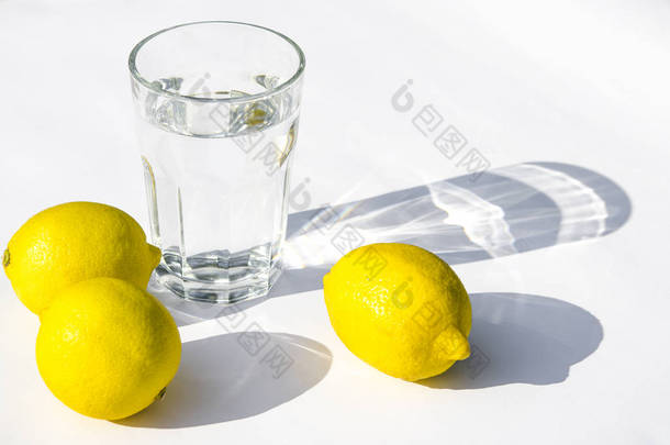柠檬，新鲜的绿色薄荷和玻璃玻璃与水在白色背景。白色背景上的阴影