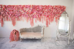 旧的雕刻沙发床与柔软的装饰与粉红色的花朵装饰白色墙壁。华丽的花环。室内装饰是浪漫的, 婚礼照片区。在镜子里模仿。全长