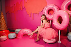 时尚工作室的照片，美丽的年轻女子，金发碧眼，穿着雅致的衣服，摆设着粉红房间，装饰着甜点