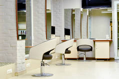 现代美容院内部及美容美发专业工作场所.在美容院里为美发师提供工作空间。浅白米色美发店的内部.
