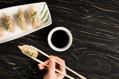 在blac，女人用筷子和酱油吃美味的中国水饺，这是一个不寻常的画面