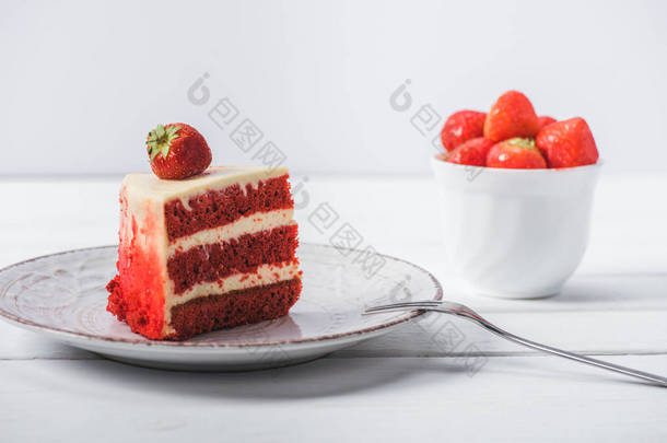 一块红色的蛋糕装饰与草莓在茶托附近的水果杯孤立在白色 