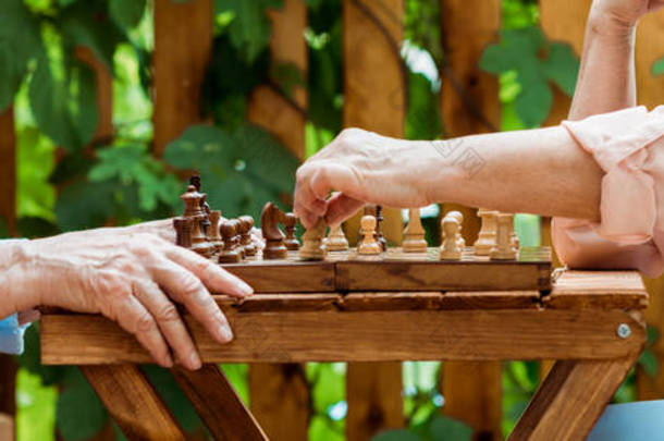 退休夫妇在木桌上下棋的全景镜头 