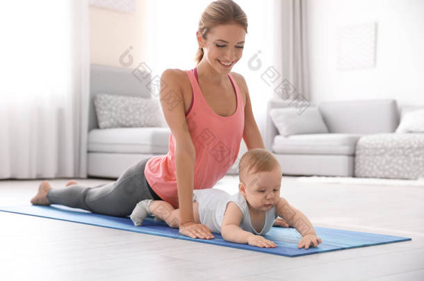 年轻的母亲在家做瑜伽与婴孩