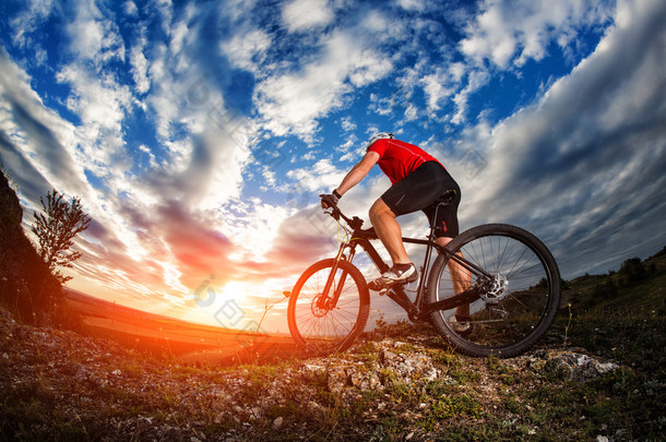 日出时的岩石小路上骑自行车的人骑山地自行车