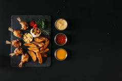 美味烤土豆烤蒜和鸡肉, 香草和沙司在黑色的顶级视图