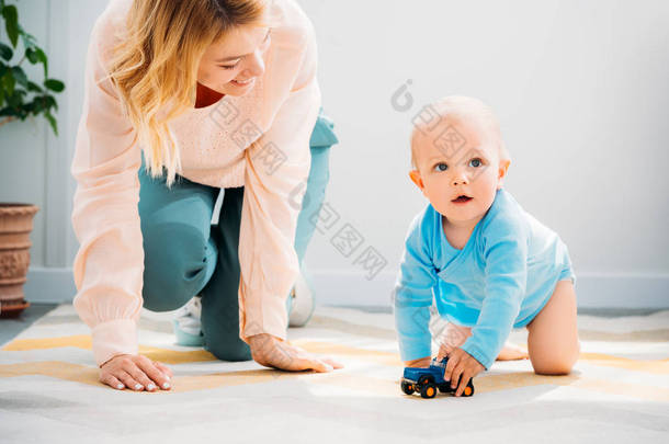 母亲和孩子在地毯上爬行在家