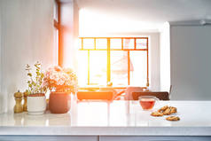 阳光明媚的早晨吃早餐的场景。透明的黑色茶杯, 厨房桌子上有饼干