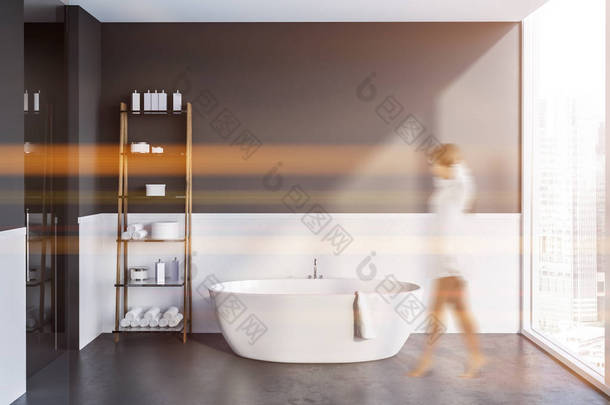 妇女在内部的<strong>现代</strong>浴室与白色和灰色的墙壁, 水泥地板, 白色浴缸和货架与毛巾和洗发水。色调图像模糊