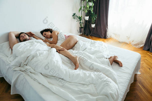 夫妇睡在床上，有白色被单复制空间
