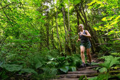 在一个充满活力的夏日里，冒险的女孩在森林里奔跑。 在加拿大不列颠哥伦比亚省温哥华北部深湾拍摄.