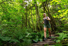 在一个充满活力的夏日里，冒险的女孩在森林里奔跑。 在加拿大不列颠哥伦比亚省温哥华北部深湾拍摄.