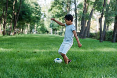 可爱的非洲裔美国孩子在绿草上踢足球 